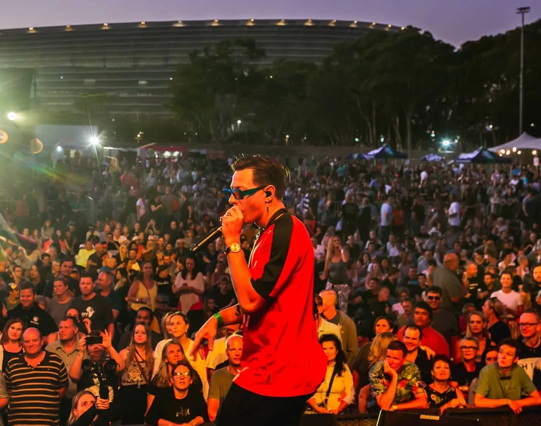 Simon Ackermann singing live in red top with blue glasses